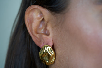 Textured gold stud earrings with faceted, molten-look rounded shape