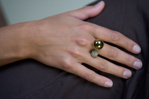 Gold dual sphere ring on hand with green gem top and pavé sphere accent