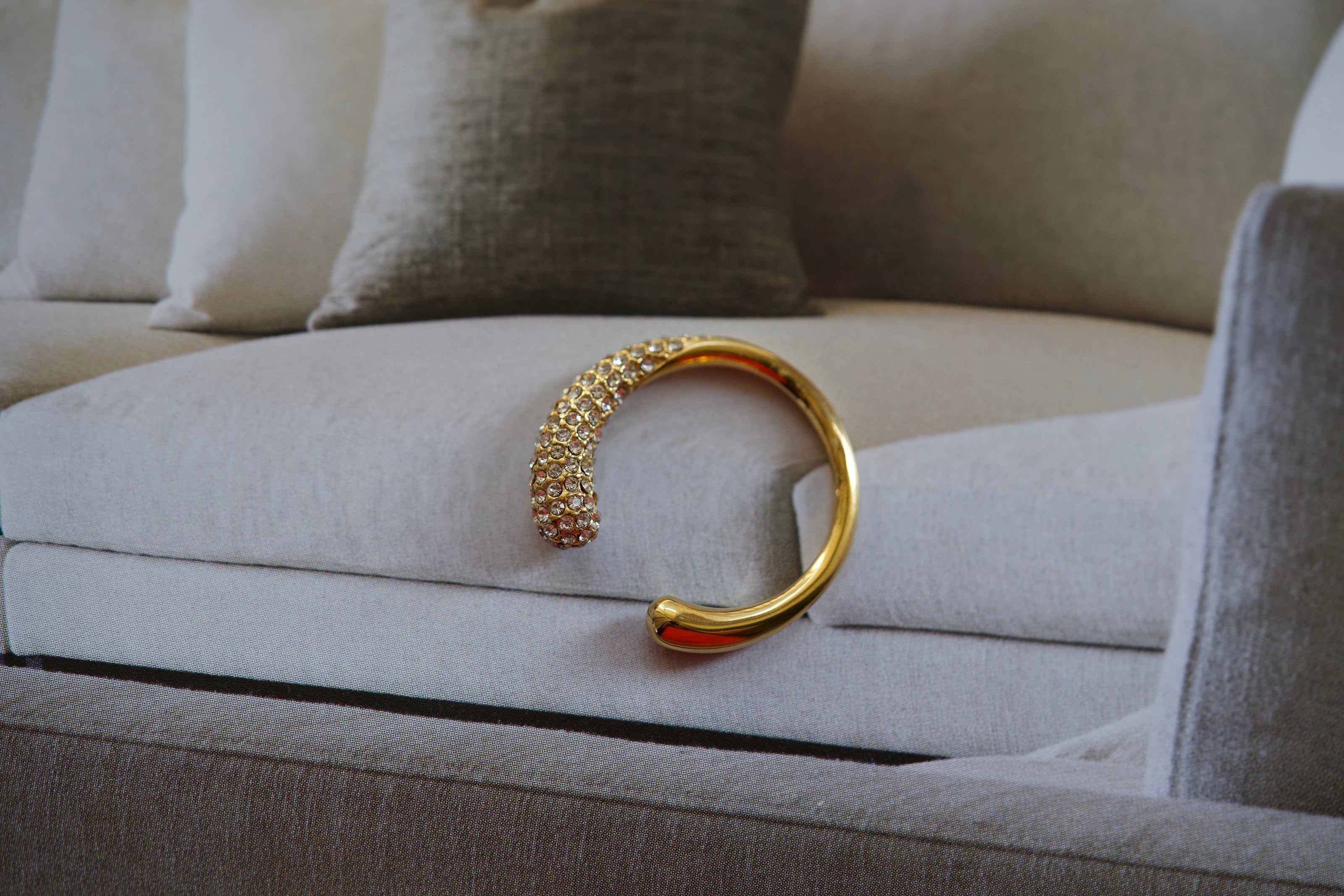 Gold-tone C-shaped crystal ring with sparkling rhinestone inset across the curve