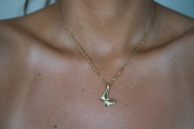 Gold butterfly pendant necklace with green enamel accents