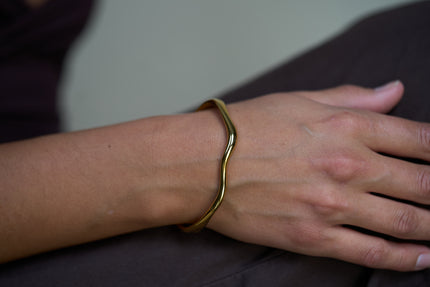 Gold wave cuff bracelet on wrist, smooth open bangle with curved ends