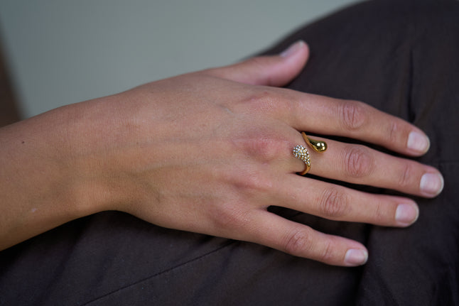 Gold dual-crystal ring on finger with small clear stones and round center