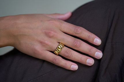 Gold sculpted heart ring on hand with stacked heart band